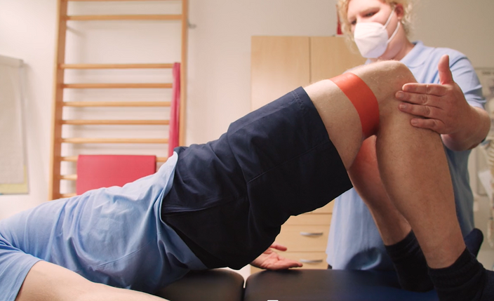 Der Ausschnitt aus dem Kollegfilm zeigt das Knie eines Patienten, das physiotherapeutisch behandelt wird.