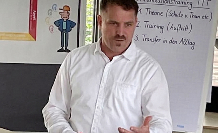 Dozent Tobias Jesse führt durch ein Kommunikationstraining mit Flipchart und Plakatwand im Hintergrund 