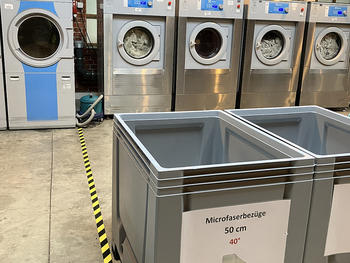 Eine Markierung auf dem Boden trennt die Bereiche mit verschmutzter und gereinigter Wäsche.
    