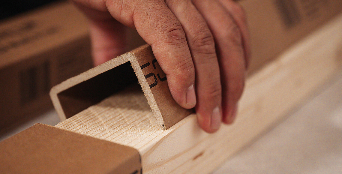 Innenansicht eines Raums im Holzrahmenbau mit freiliegenden Holzständern und Wandplatten im Rohbau. 
