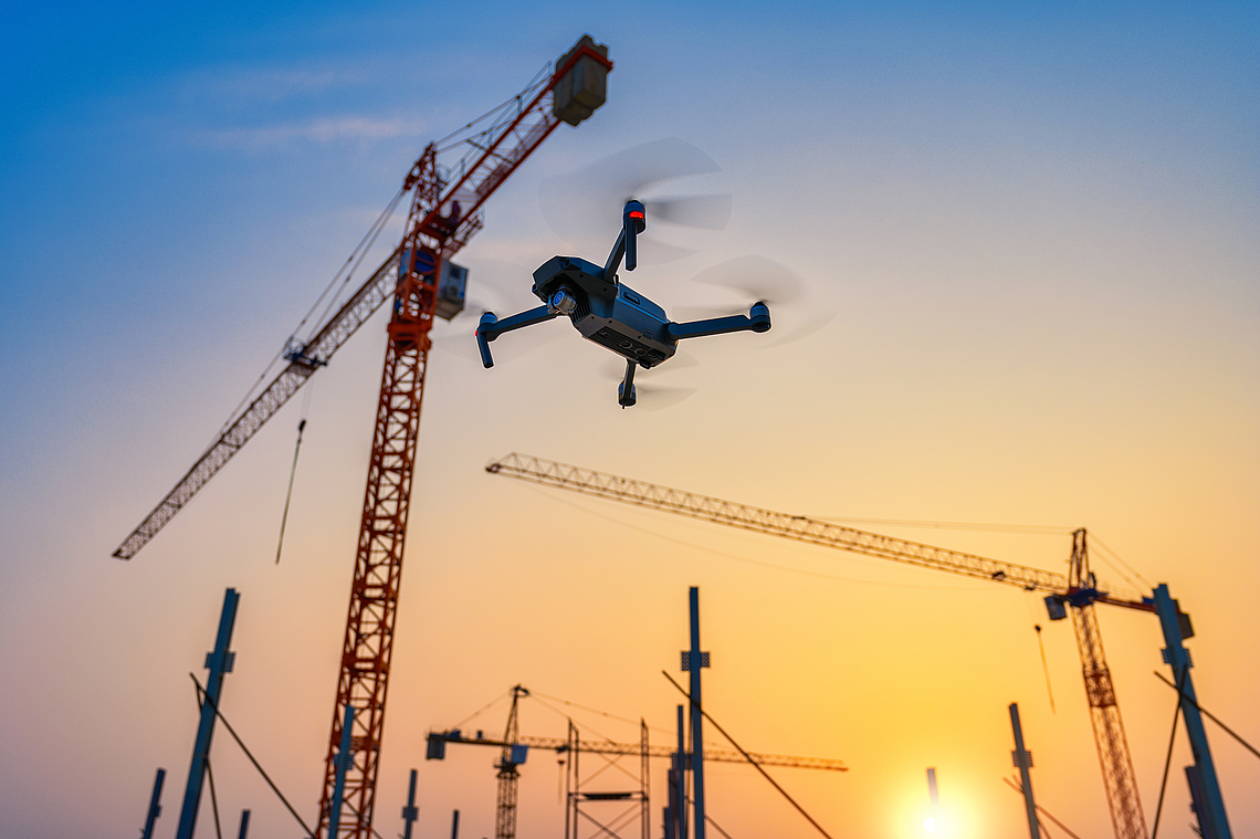 Eine Drohne fliegt über einer Baustelle.
