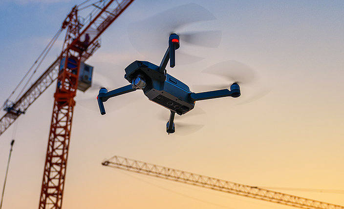 Eine Drohne fliegt über einer Baustelle.
