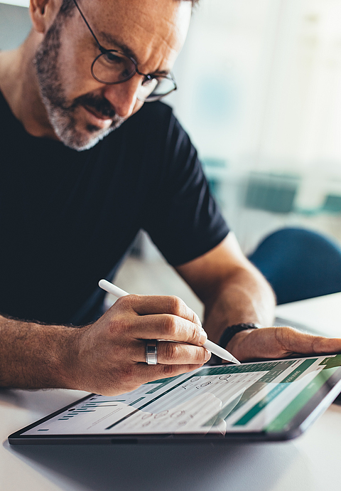 Mann arbeitet am Tablet. 