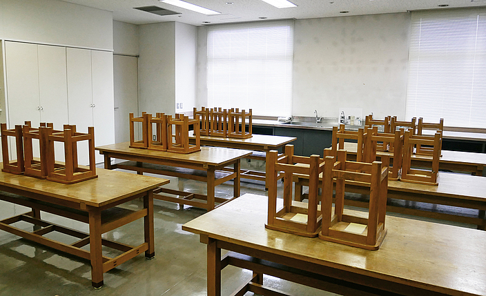 Ein leeres Klassenzimmer mit hochgestellten Stühlen.