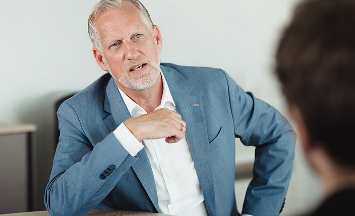 Björn Kass, Präventionsleiter der BG BAU, im Dialog mit einem Gesprächspartner, der mit Unschärfe von hinten abgebildet ist.