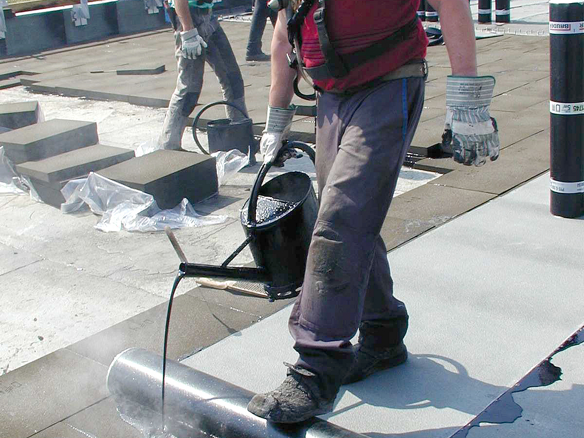 Mann wird beim Arbeiten mit Dachpappe durch Bitumen-Dämpfe gefährdet.
