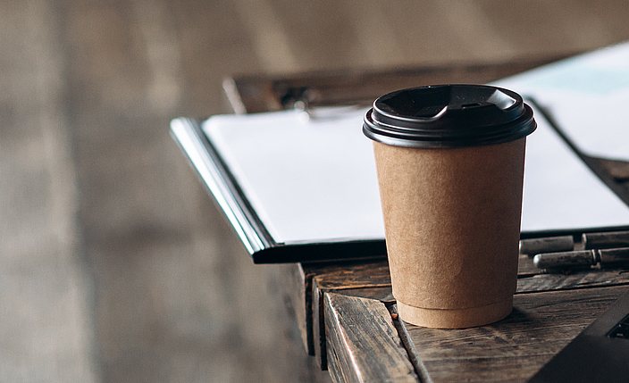 Ein Kaffeebecher steht auf einem Tisch.