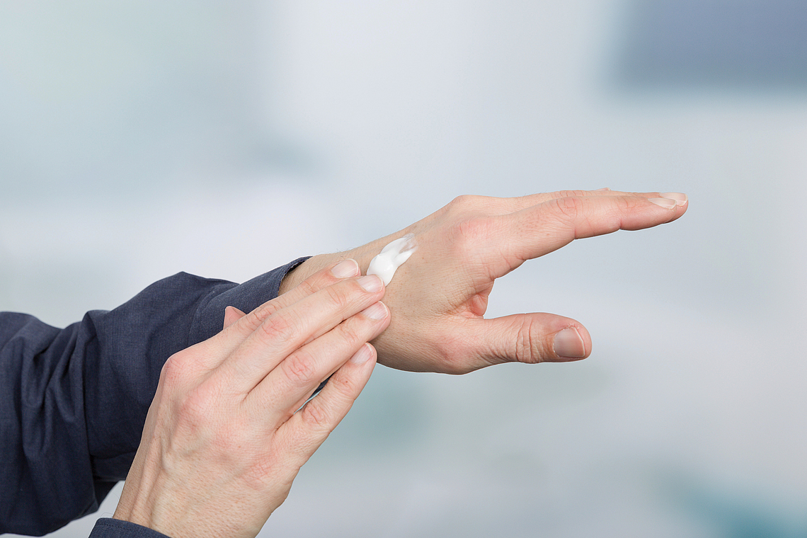 Eine Person cremt sich die Hände mit Sonnenschutzcreme ein, um einer Berufskrankheit vorzubeugen. 