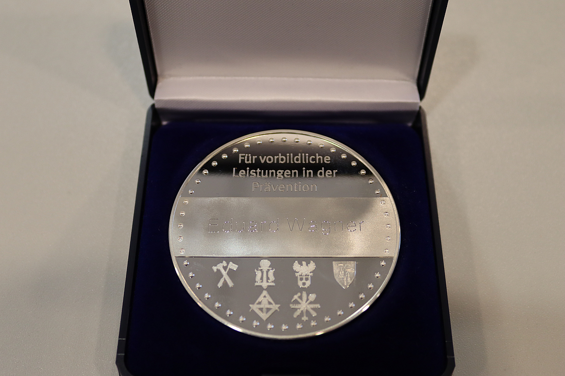 Die BG BAU-Auszeichnung Medaille "Sicherheit am Bau" in einem geöffneten Etui.
