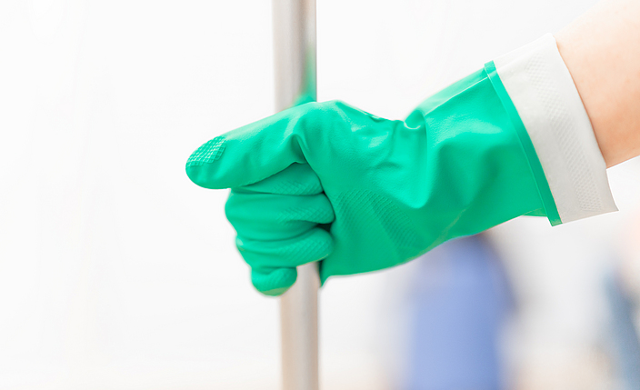 Eine Hand mit einem grünen Chemikalienschutzhandschuh hält einen Stil. 