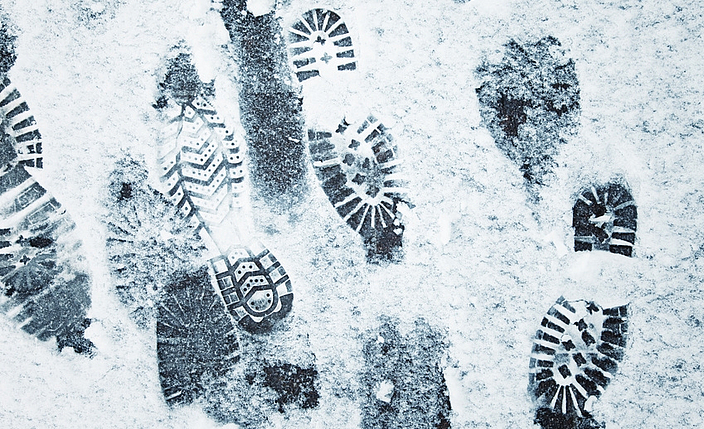 Auf einem Boden sind verschiedene Fußabdrücke im Schnee.