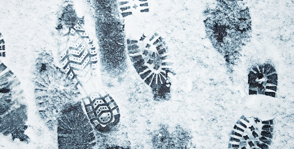 Auf einem Boden sind verschiedene Fußabdrücke im Schnee. 