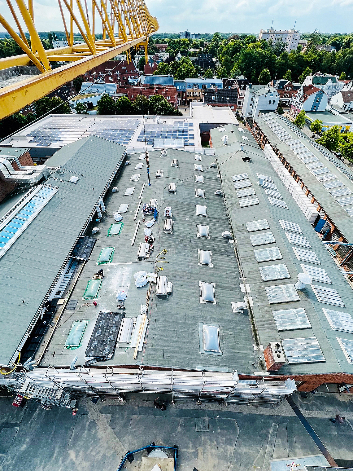 Aufnahme der Dachflächen von oben aus Kranperspektive. Ein Teil der Lichtkuppeln ist schon mit grünen Netzen umspannt. 