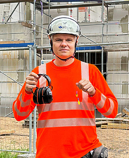 Porträt Jens Möller mit Gehörschutz, Aufsichtsperson der BG BAU.
