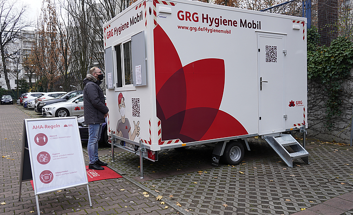 Mann steht vor GRG-Hygienemobil, einer mobilen Corona-Teststation