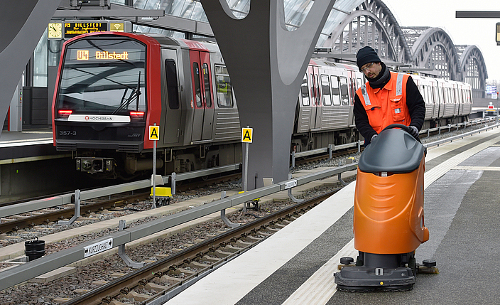 Mann bedient Reinigungsmaschine auf einem Bahnsteig der Hamburger S-Bahn.