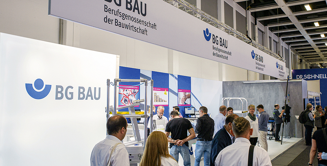 Besucher am Messestand der BG BAU. 